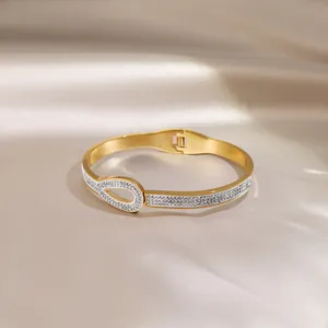 Close-up of golden stainless steel bangle with pavé crystals on champagne silk