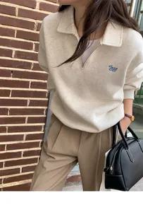 Detail of oatmeal half-zip polo sweatshirt with blue Jazz or not embroidery and vintage wall