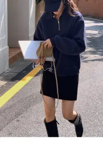Outdoor street style view of navy half-zip sweatshirt with black skirt and high boots