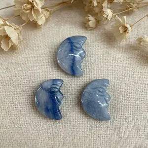 Macro shot of three hand-carved blue stone moon face pendants on a linen background