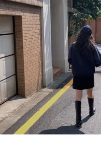 Outdoor street style view of navy polo sweatshirt with black skirt and leather boots