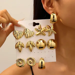 Close-up of gold C-shaped earring set featuring starfish and leaf-shaped metal designs