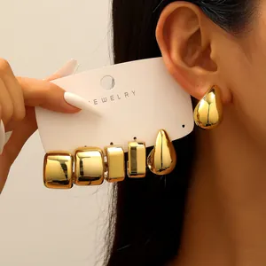 Macro view of gold geometric stud earrings and teardrop hoops on jewelry display card