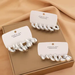 Macro shot of silver C-shape earring set with spiral and drop designs on display card