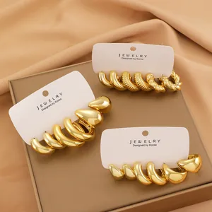 Close-up of chunky gold hoop earrings set with spiral texture on white card
