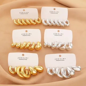 Macro shot of chunky gold and silver C-shaped hoop earrings set on display card