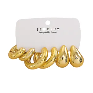 Detailed view of chunky gold hoop and teardrop earrings set on a white display card