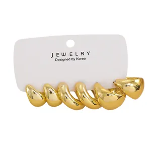 Close-up of thick gold twisted hoop earrings with a high-polished metallic mirror finish