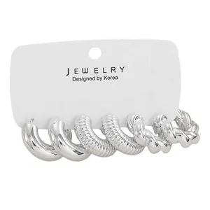 Close-up of three pairs of silver hoop earrings including smooth, ribbed, and twisted styles