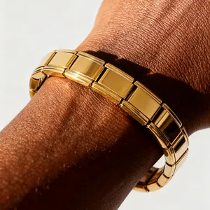 Nahaufnahme eines vergoldeten Edelstahl-Charm-Armbands am Handgelenk eines Models