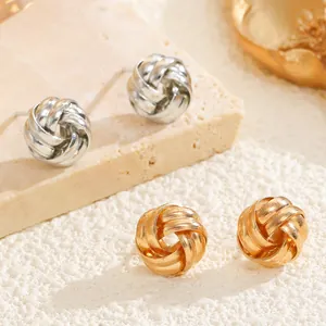Detail shot of gold and silver twisted love knot stud earrings on a textured stone base