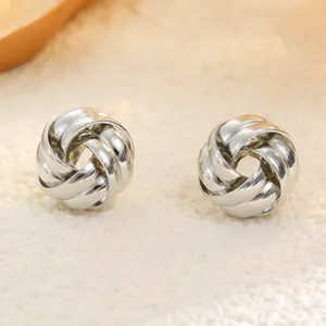 Macro shot of silver knot stud earrings showing detailed intertwined metallic texture