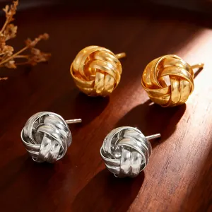 Close-up of gold and silver twisted knot earrings with a brushed metal texture