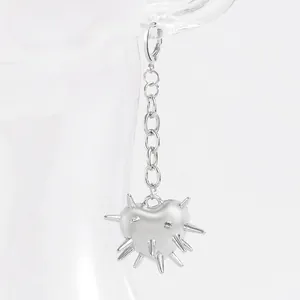 Détail de boucle d'oreille cœur argenté avec pointes punk et chaîne sur un support