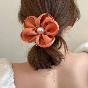 Orange floral satin hair scrunchie with pink pearl center worn on a model hair