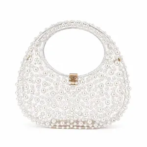 Detail of transparent acrylic handbag with white faux pearl embellishments and gold clasp