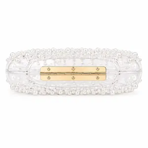 Macro detail of clear acrylic evening bag featuring layered white pearls and gold hinge