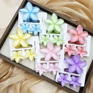 Frangipani hair clip set in vibrant colors displayed on golden silk fabric background