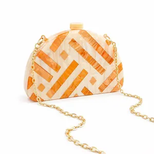 Semi-circular acrylic clutch with orange stripes and gold chain strap for evening events