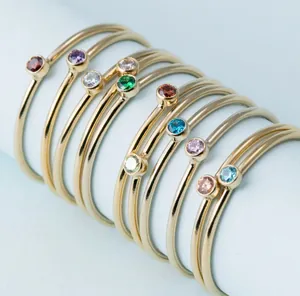 Macro shot of minimalist gold rings set with colorful gemstones on a blue stand