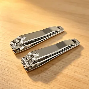 Detailed view of two professional stainless steel nail clippers on a warm wooden surface