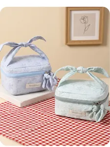 Close-up of floral embossed makeup bags with bow handles in light blue and green colors