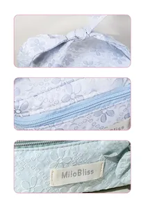 Detail of mint green makeup bag with floral embroidery and bow handle accents