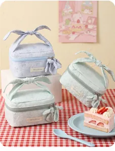 Detail of floral jacquard cosmetic bags with large bow handles in light blue and green