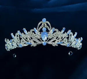 Close-up of a silver baroque crown with blue teardrop stones on dark velvet background