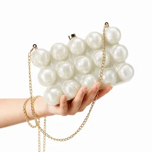 Detail shot of the golden metal clasp and chain strap on a white pearl acrylic clutch bag