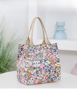 Detail of pink canvas tote with cat prints and light brown woven handles on a desk