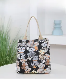 Detail view of canvas tote bag with cat prints and woven rope handles on white table
