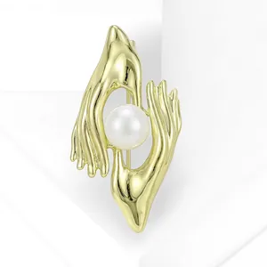 Close-up of creative gold hand-holding pearl brooch for suit accessories.