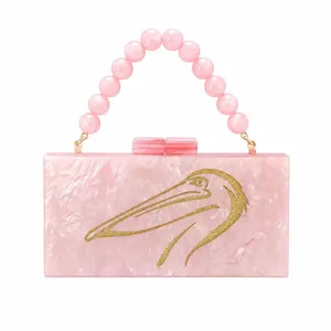 Detailed macro of pink marble acrylic evening bag with gold pelican bird and bead handle