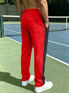 Detail of men's red joggers with black side stripes and back pocket in a sports setting