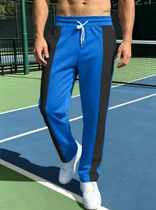 Detail of blue and black color-block men's athletic joggers on a tennis court