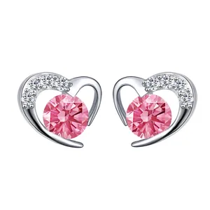 Close-up of heart-shaped earrings featuring a large pink gemstone and silver metal