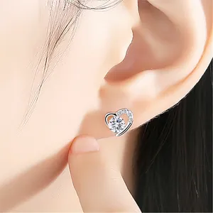 Close-up of heart-shaped silver earrings with sparkling cubic zirconia on earlobe