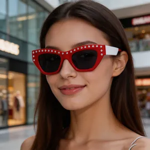 Close-up of red cat eye sunglasses with rhinestone trim and white contrast temples
