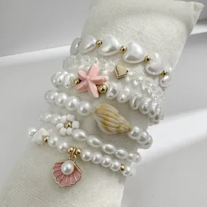 Vue détaillée de bracelets de perles empilés avec breloques étoile de mer et coquillage