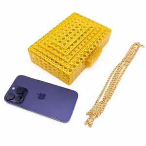 Detail of yellow woven acrylic clutch showing size comparison with a mobile phone