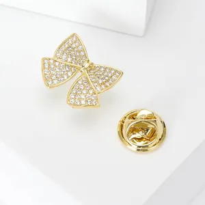 Macro detail of a golden bow brooch with pavé zircon stones and butterfly pin backing
