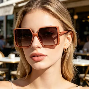 Detail of oversized square sunglasses with coral frames and gold temple accents