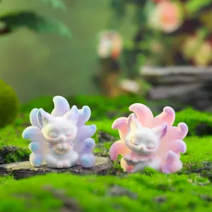 Detail of two nine-tailed fox figurines with blue and pink gradients on natural moss