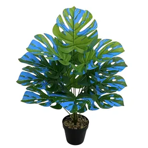 Close-up of artificial Monstera plant with unique blue and green variegated leaves potted