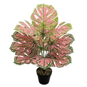 Detail view of pink and green artificial monstera plant in black pot for home decor