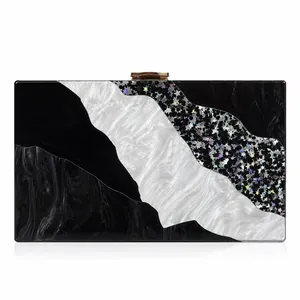 Detail of acrylic clutch with black marble pattern and holographic star sequence inlay