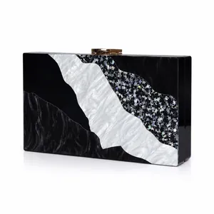 Detail of acrylic evening clutch with black and white wavy patterns and gold metal clasp