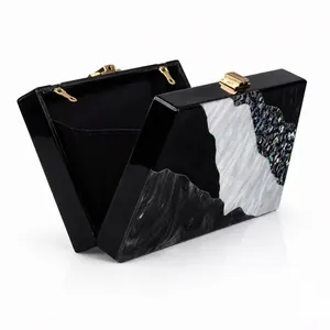 Detail of color block acrylic evening clutch with marble pattern and gold metal clasp