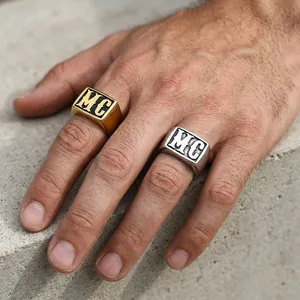 Macro shot of silver and gold men's signet rings with MC engraving on a stone surface